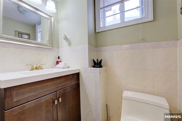 half bathroom with vanity, toilet, and tile walls