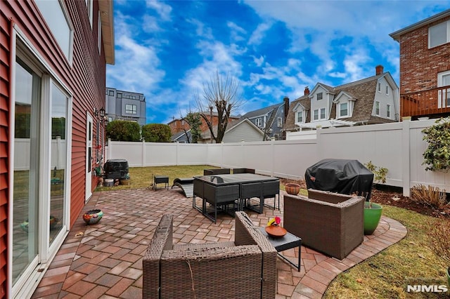 view of patio featuring a grill, a residential view, an outdoor living space, and a fenced backyard