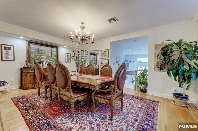 dining space featuring ornamental molding, light wood-type flooring, visible vents, and baseboards