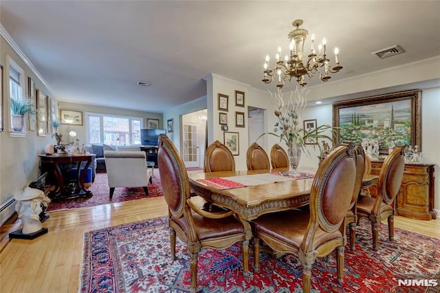 dining room featuring wood-type flooring, visible vents, and crown molding