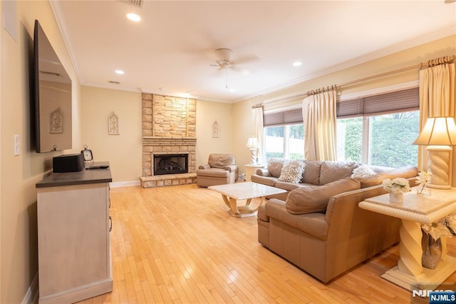 living area featuring light wood finished floors, a fireplace, crown molding, and a ceiling fan