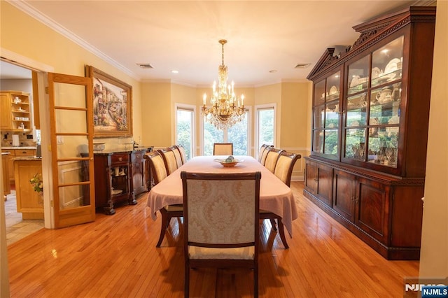 dining space featuring visible vents, an inviting chandelier, light wood-style floors, and ornamental molding