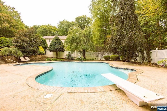 view of swimming pool featuring a diving board, a fenced in pool, a patio, and a fenced backyard