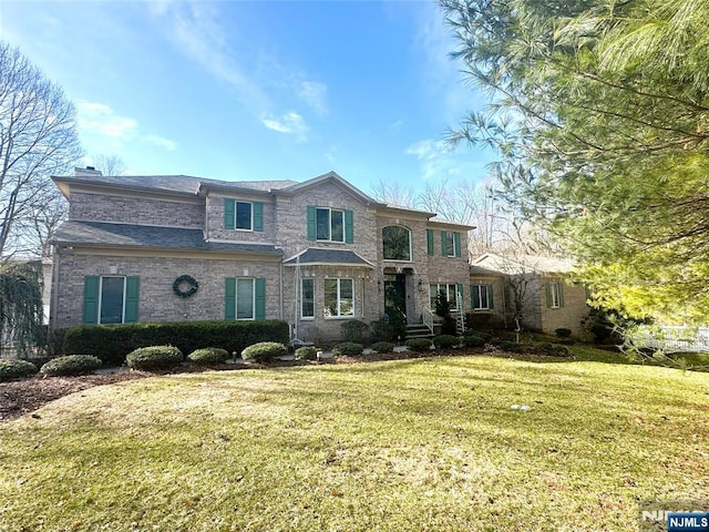 view of front of house with a front lawn, brick siding, and a chimney