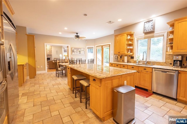 kitchen featuring a kitchen island, open shelves, a sink, stainless steel appliances, and backsplash