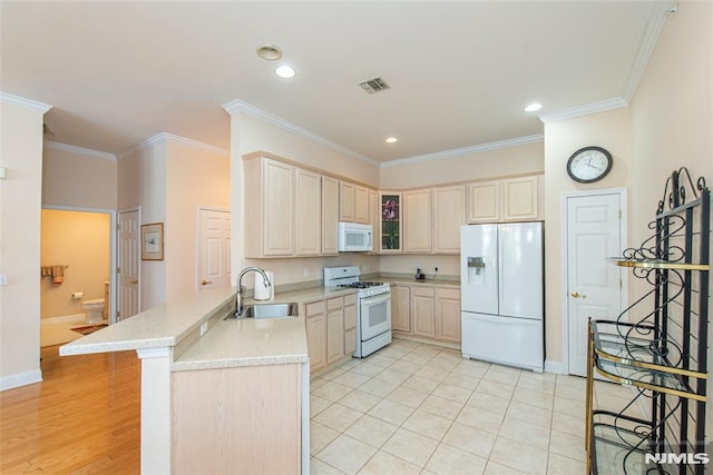 kitchen featuring white appliances, crown molding, a peninsula, and a sink