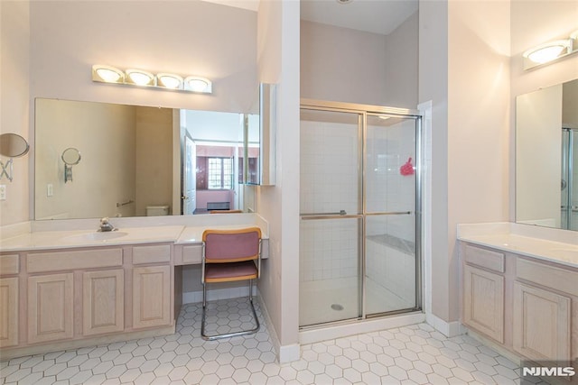 full bath with tile patterned flooring, a stall shower, two vanities, and a sink