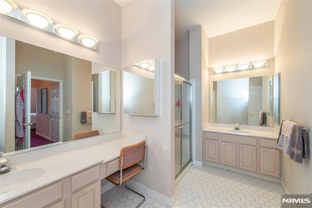 full bath featuring a shower stall, two vanities, tile patterned floors, and a sink