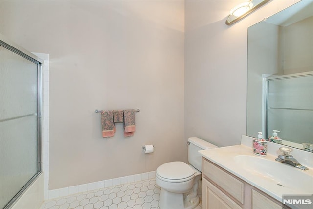 bathroom with tile patterned floors, toilet, baseboards, enclosed tub / shower combo, and vanity