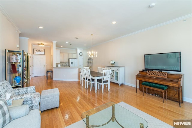 living area with baseboards, recessed lighting, crown molding, light wood-type flooring, and a chandelier