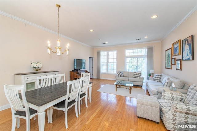 dining space with visible vents, baseboards, ornamental molding, light wood-style flooring, and an inviting chandelier