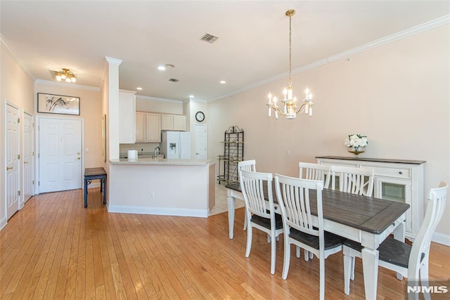 dining area featuring ornamental molding, visible vents, light wood finished floors, and a chandelier