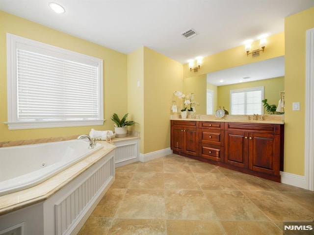 bathroom featuring double vanity, visible vents, a sink, a jetted tub, and baseboards