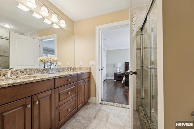 bathroom with a sink, double vanity, a shower stall, and baseboards