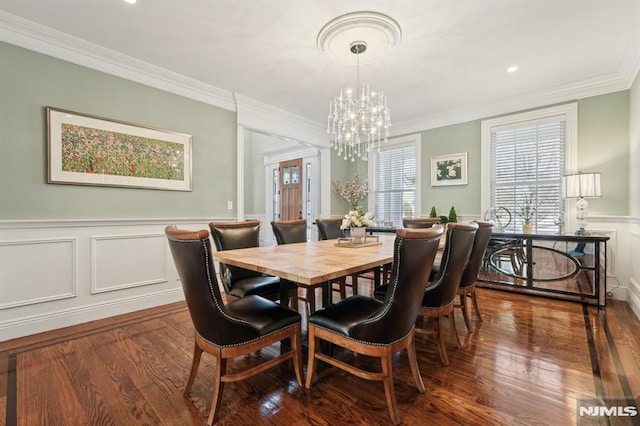 dining room featuring crown molding, a chandelier, dark wood-type flooring, and wainscoting