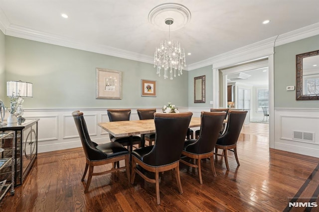 dining space featuring visible vents, dark wood finished floors, crown molding, and a decorative wall