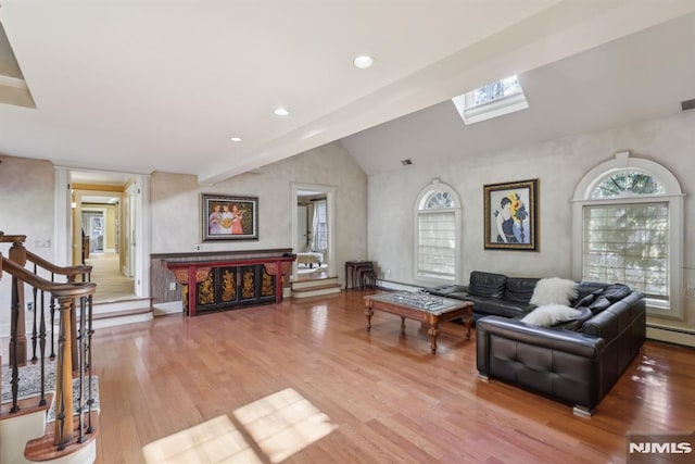 living room with vaulted ceiling with skylight, stairway, wood finished floors, and recessed lighting