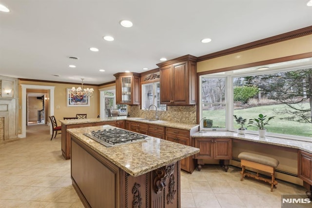 kitchen with stainless steel gas stovetop, decorative backsplash, ornamental molding, a sink, and a peninsula