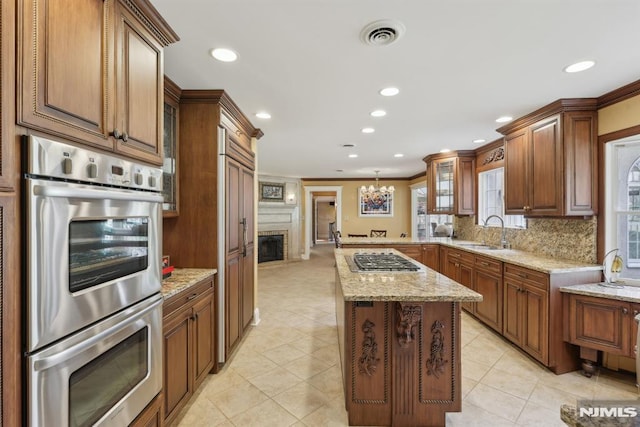 kitchen with ornamental molding, appliances with stainless steel finishes, a sink, and a center island