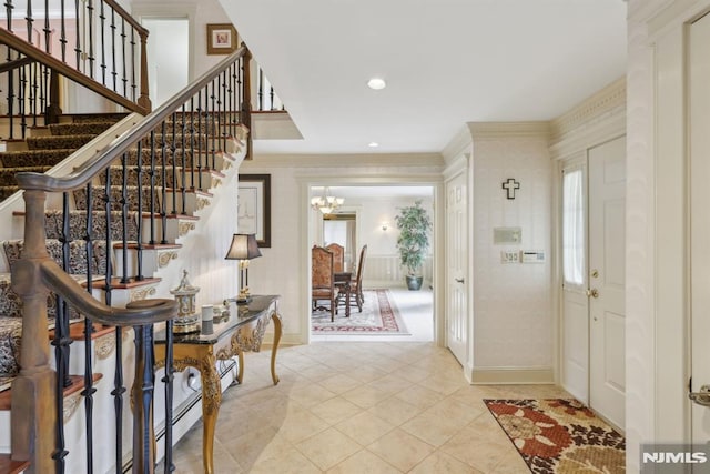 foyer with a chandelier, light tile patterned floors, crown molding, and baseboards