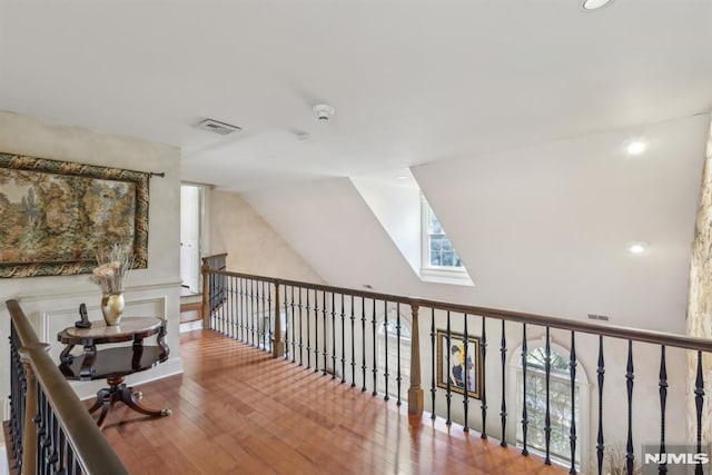 hall featuring hardwood / wood-style flooring, visible vents, and vaulted ceiling