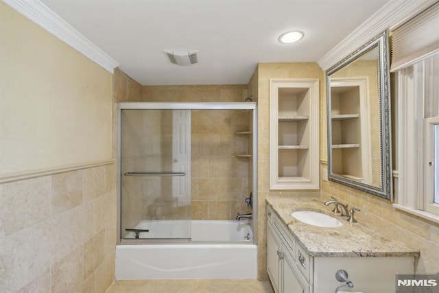 bathroom with visible vents, vanity, tile walls, built in features, and combined bath / shower with glass door