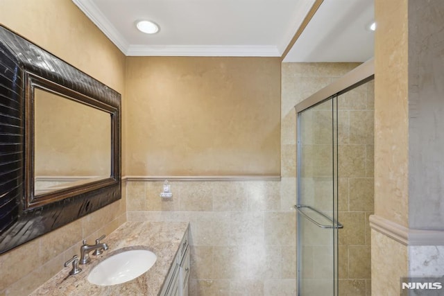 bathroom featuring a stall shower, crown molding, vanity, and tile walls