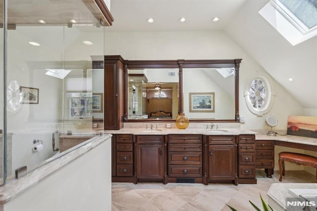 bathroom featuring vaulted ceiling with skylight, double vanity, a sink, and a bathing tub