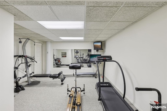 workout area with a paneled ceiling and baseboards