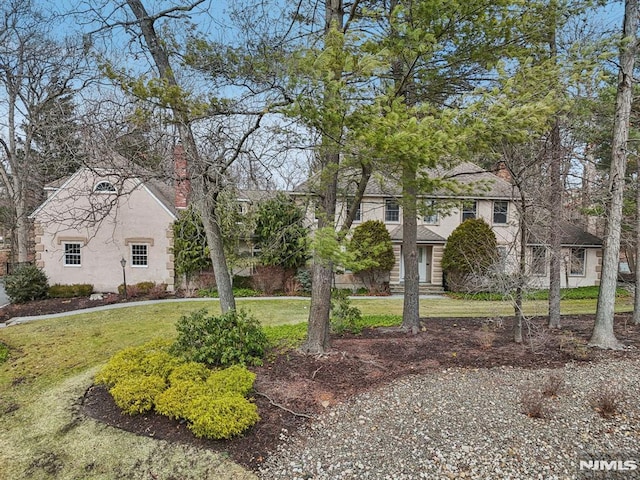 view of front of home with stucco siding, a chimney, and a front yard