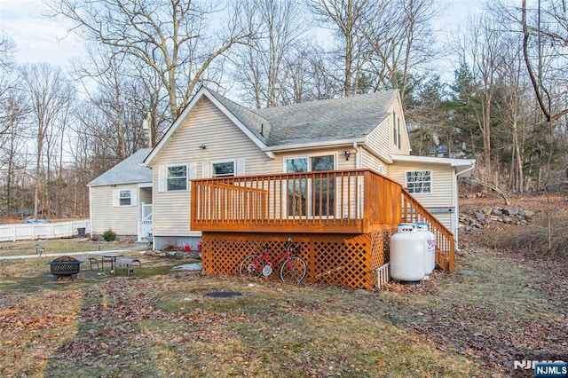 rear view of property featuring a shingled roof, an outdoor fire pit, and a wooden deck