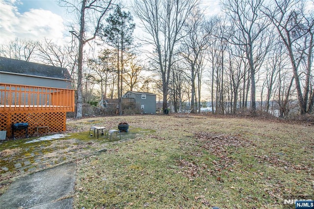 view of yard featuring a storage shed, an outbuilding, and a wooden deck