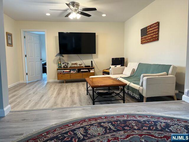 living room featuring ceiling fan, baseboards, wood finished floors, and recessed lighting