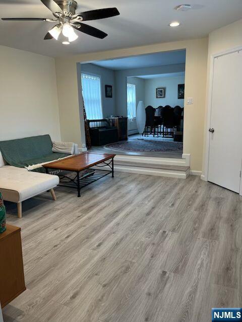 living room featuring wood finished floors, a ceiling fan, and baseboards