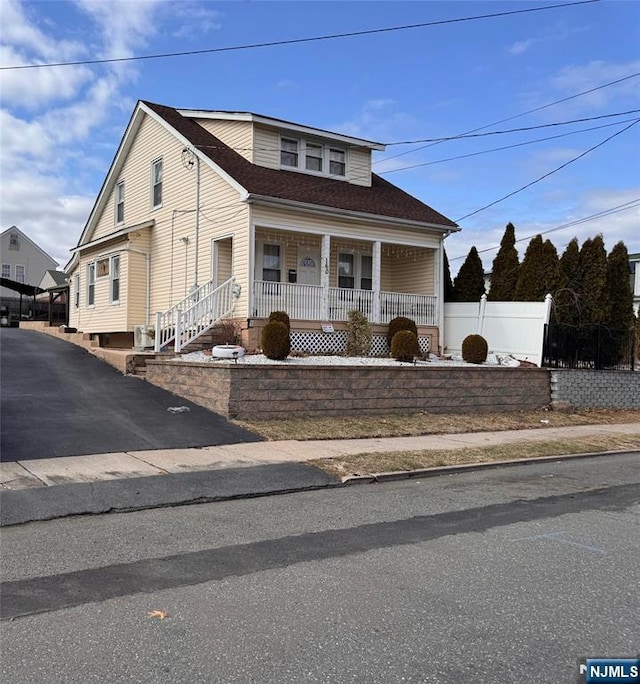 bungalow-style house featuring a porch, roof with shingles, and fence