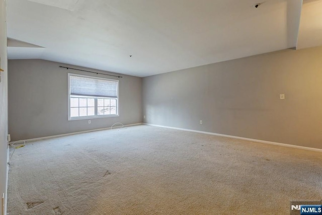 carpeted empty room with lofted ceiling and baseboards