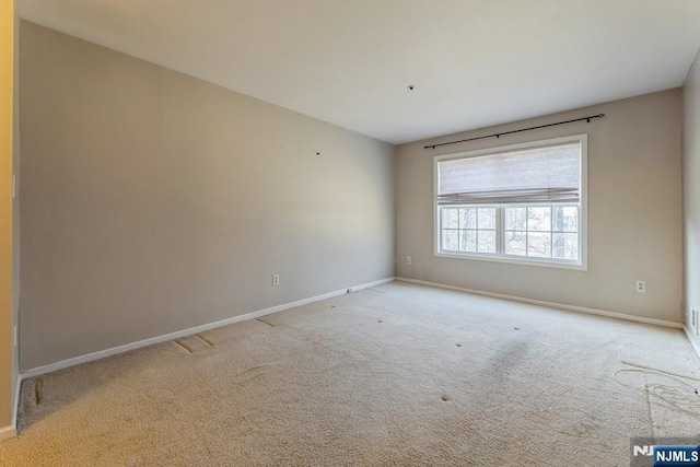 unfurnished room featuring baseboards and light carpet