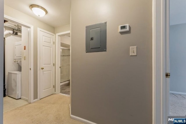 hallway with electric panel, baseboards, stacked washer / drying machine, and light carpet