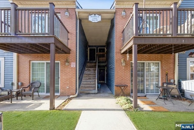 property entrance featuring a patio and brick siding