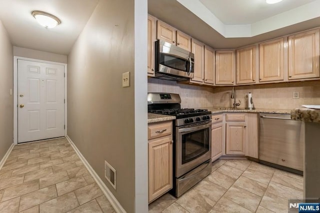 kitchen featuring decorative backsplash, light brown cabinets, and stainless steel appliances