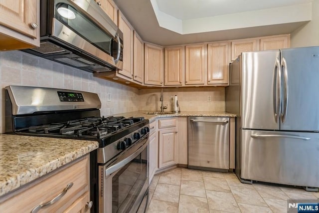 kitchen featuring a sink, light brown cabinets, tasteful backsplash, and stainless steel appliances