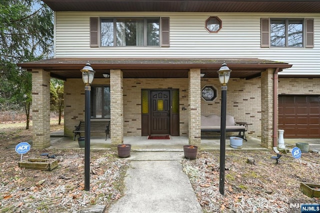 view of front of property with a garage, brick siding, and a porch