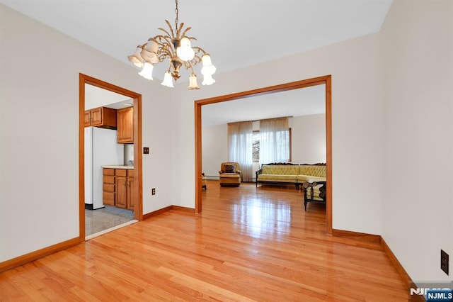 unfurnished dining area with baseboards, light wood-style floors, and an inviting chandelier