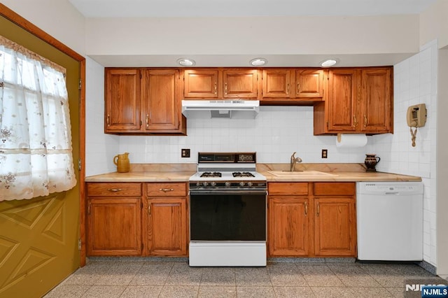 kitchen featuring light countertops, granite finish floor, a sink, ventilation hood, and white appliances