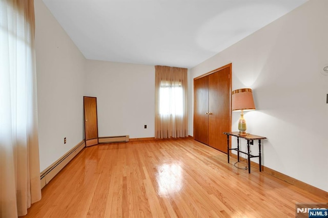 interior space featuring a baseboard radiator, a closet, light wood-style flooring, baseboard heating, and baseboards