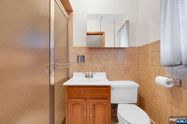 full bathroom with tile walls, a shower stall, toilet, and vanity