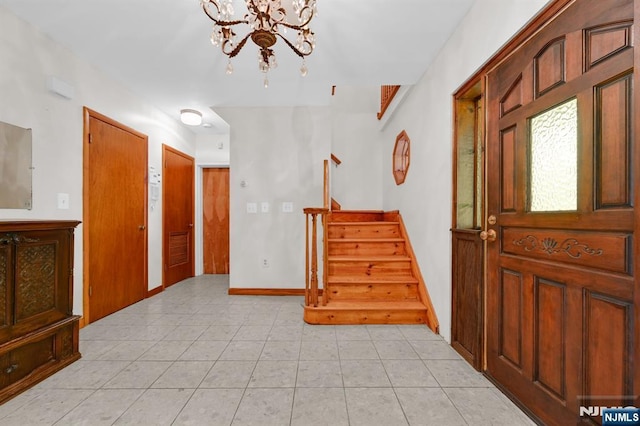 foyer featuring light tile patterned floors, visible vents, a chandelier, baseboards, and stairs