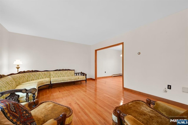 living room with a baseboard radiator, light wood-style flooring, and baseboards