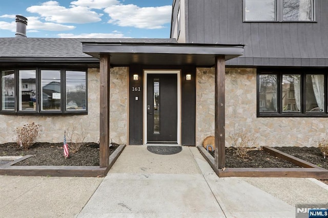 property entrance with stone siding and roof with shingles