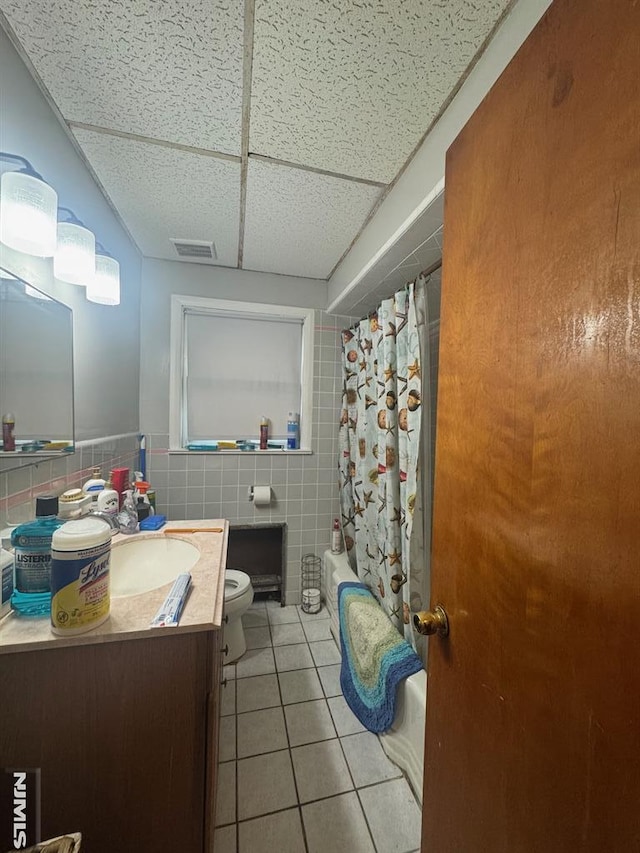 bathroom with tile patterned flooring, toilet, a paneled ceiling, vanity, and visible vents